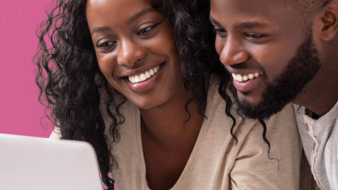 Vader en moeder kijken samen lachend naar laptopscherm