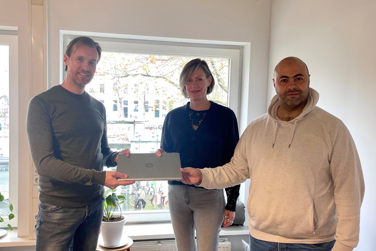 ICT medewerkers van CJG Rijnmond overhandigen laptop aan IMC Weekendschool