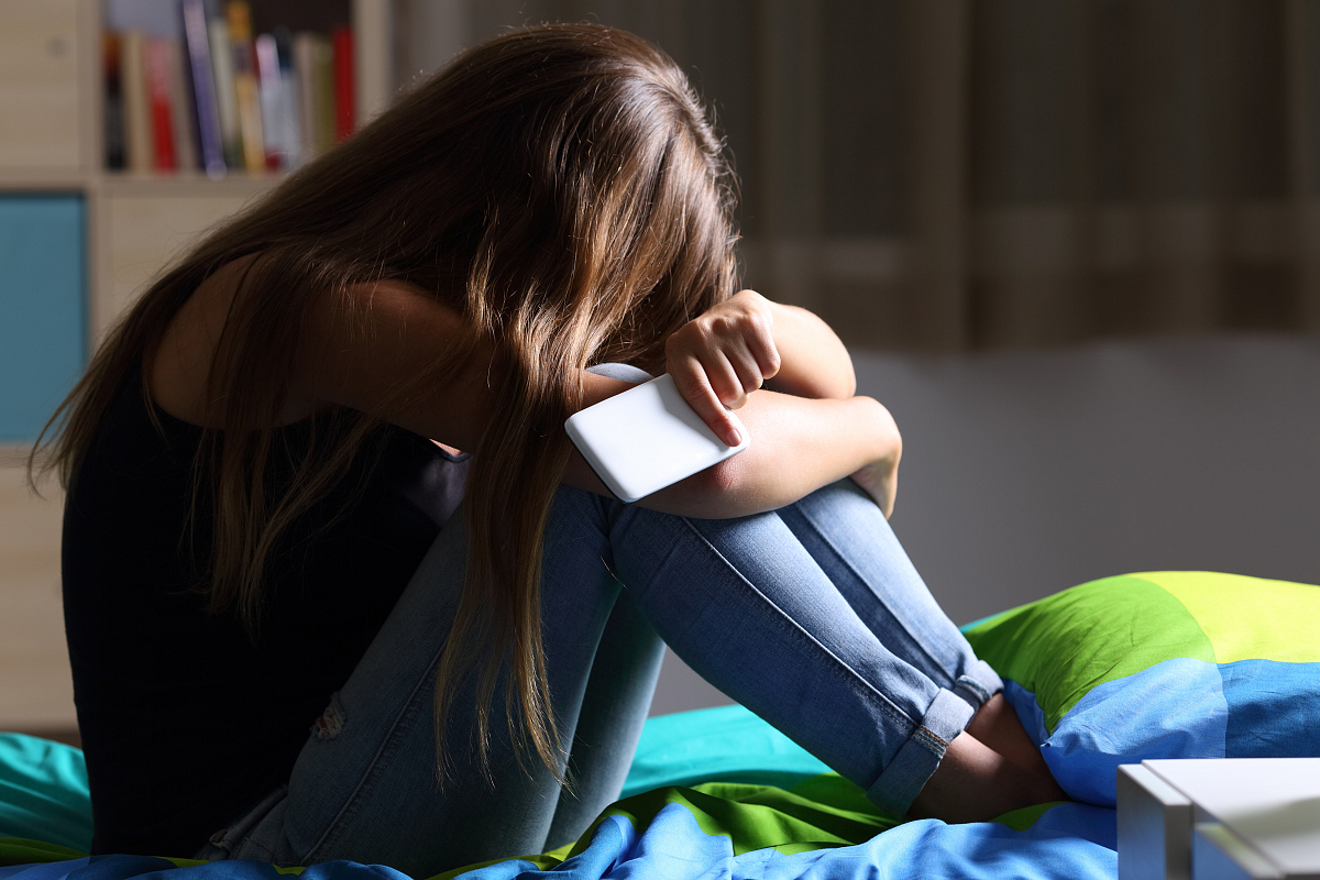 Meisje ineengedoken op bed