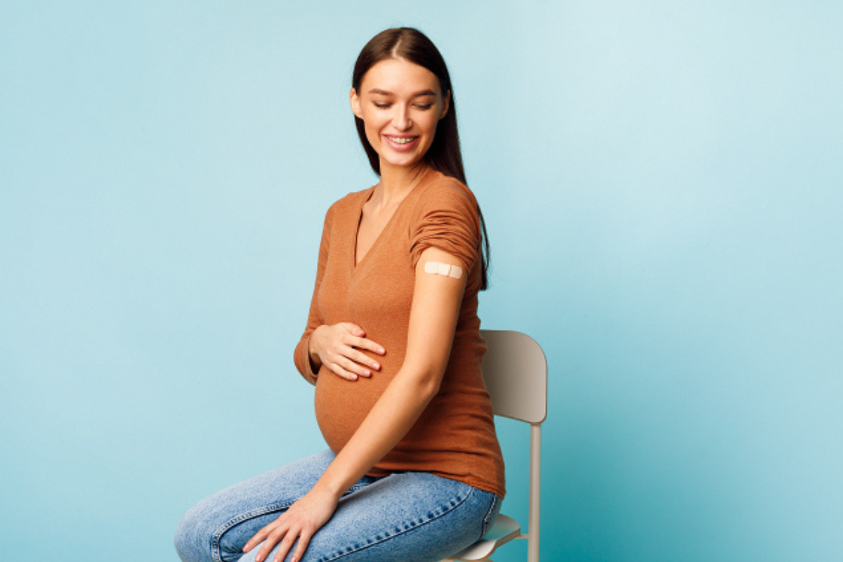 Zwangere op stoel met pleister op arm
