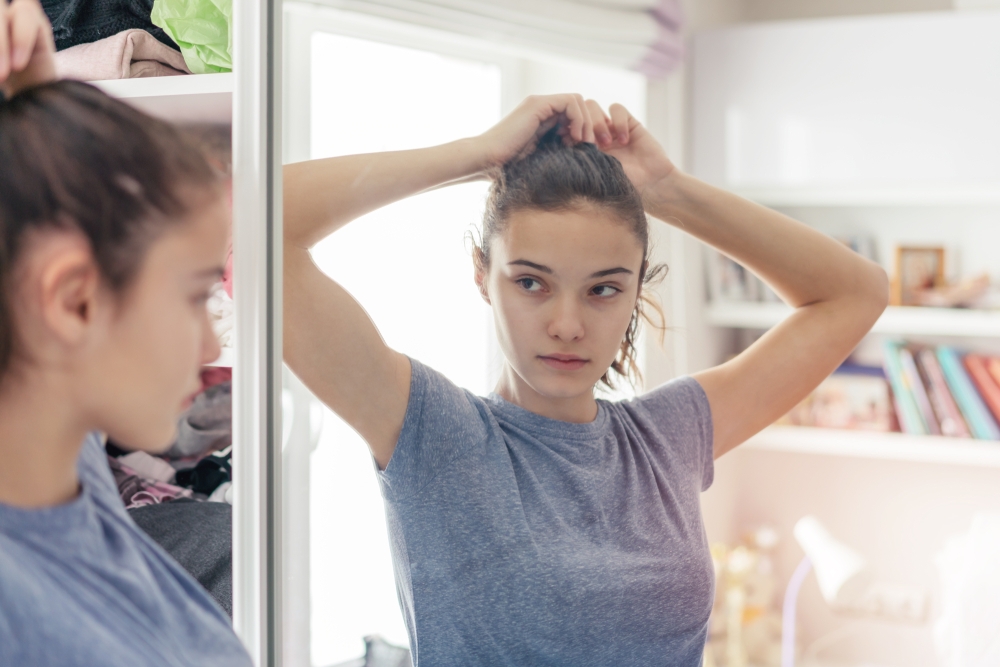 Meisje kijkt in de spiegel en doet haar haar goed