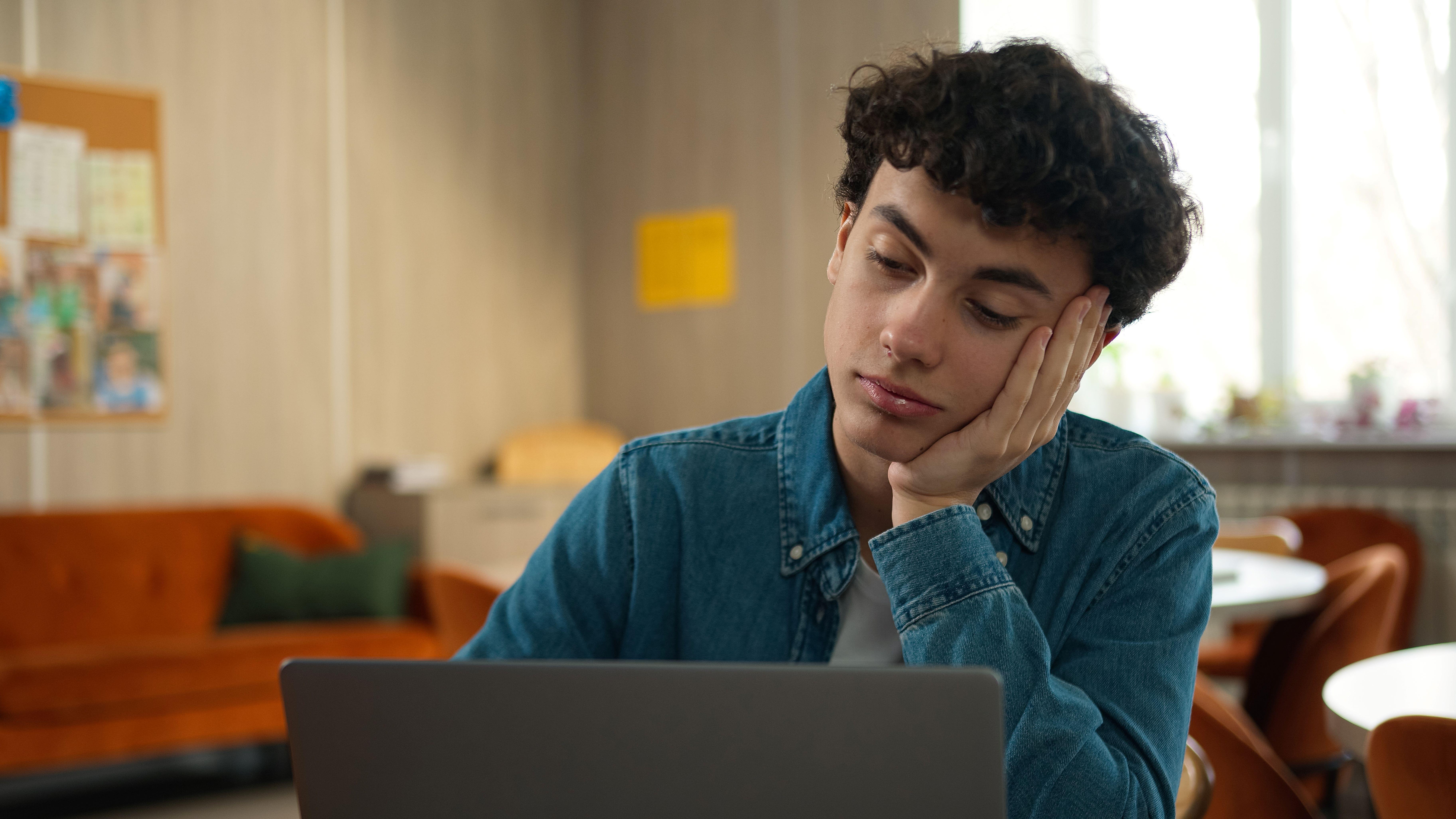 Jongen kijkt denkend naar zijn laptopscherm