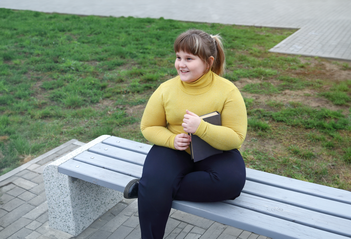 Meisje zit op bankje buiten en lacht