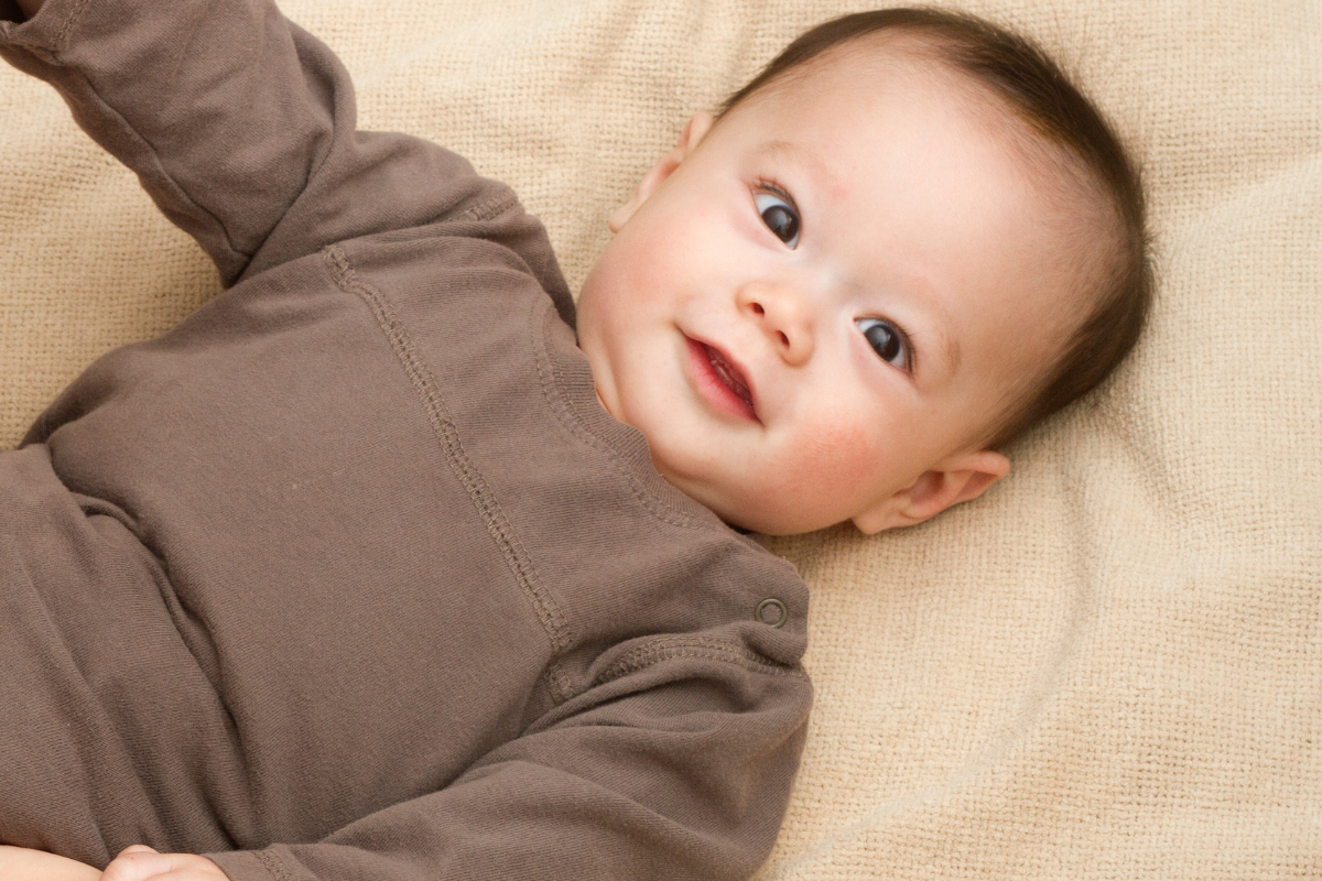 Baby kijkt lachend in de camera