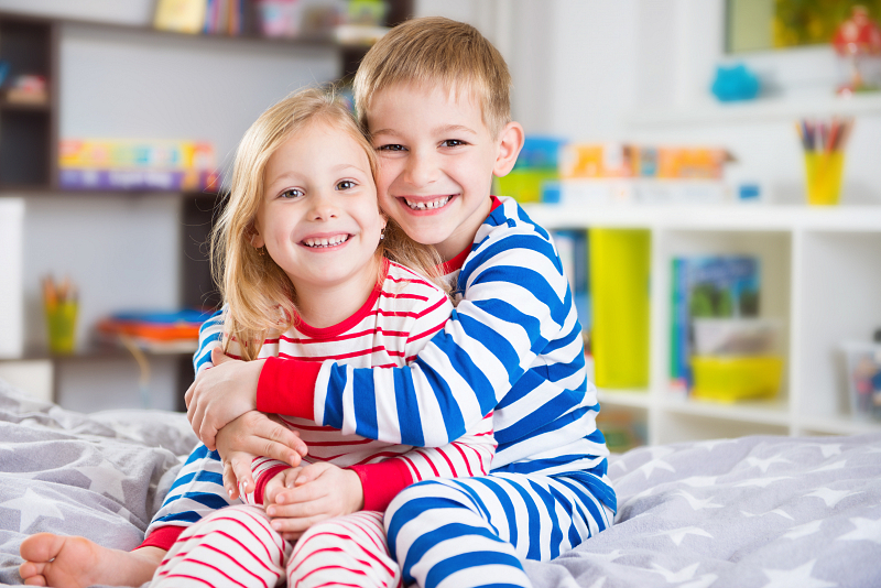 Broertje en zusje in bij elkaar passende pyjama's omhelzen elkaar