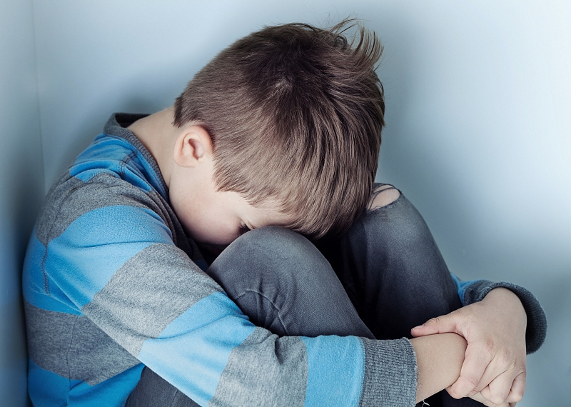 Kind zit verdrietig met hoofd naar beneden