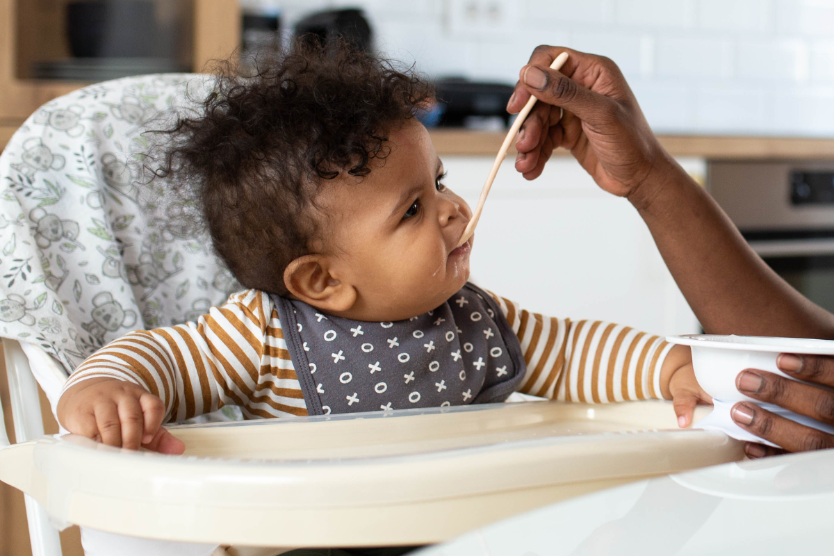 Baby zit in kinderstoel en krijgt hapje