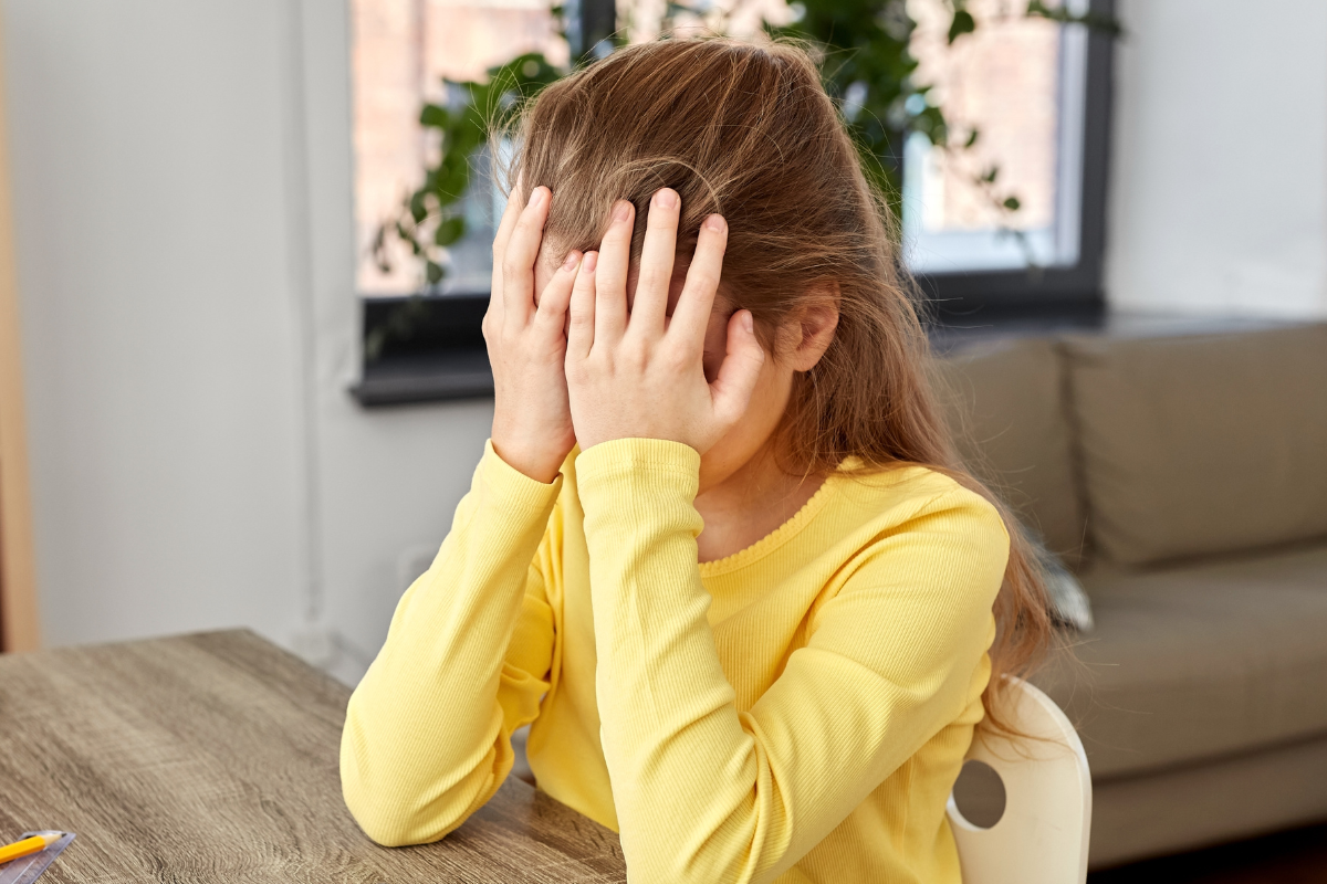 Meisje zit gefrustreerd met handen voor haar ogen