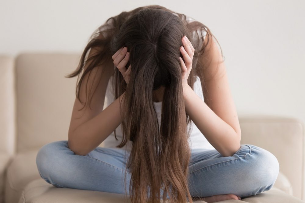 Meisje zit met handen in het haar en is gefrustreerd