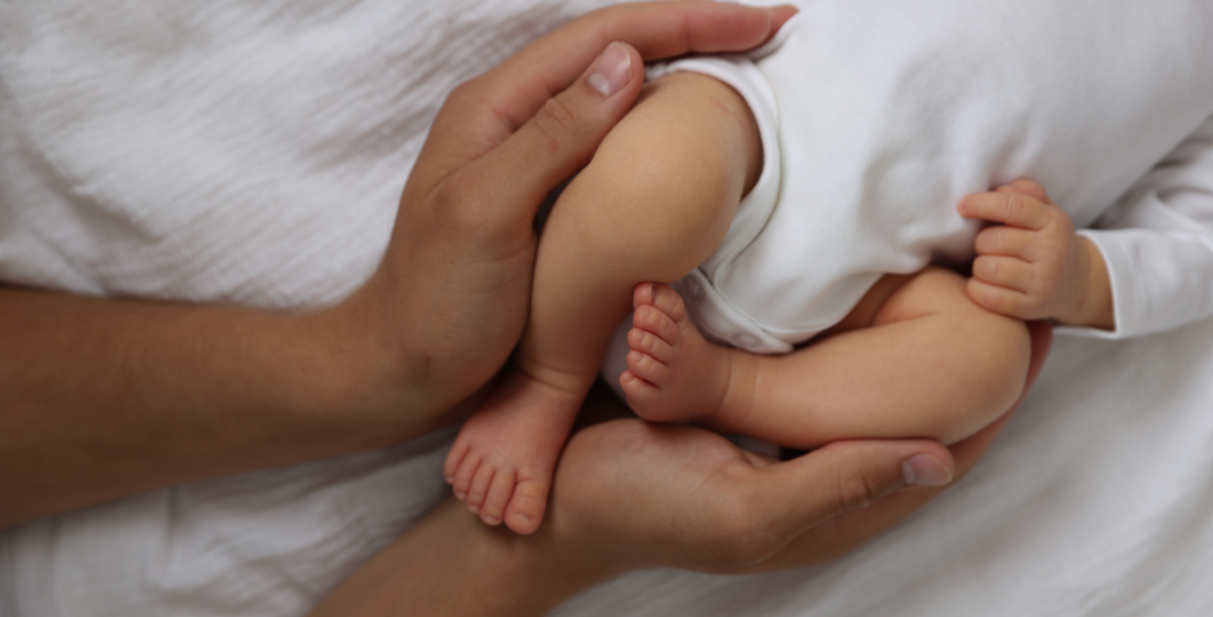 Ouder die heupen van baby vasthoudt