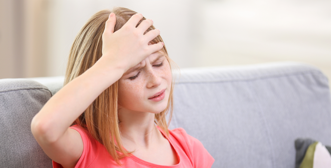 Meisje die naar haar hoofd grijpt en pijnlijk kijkt