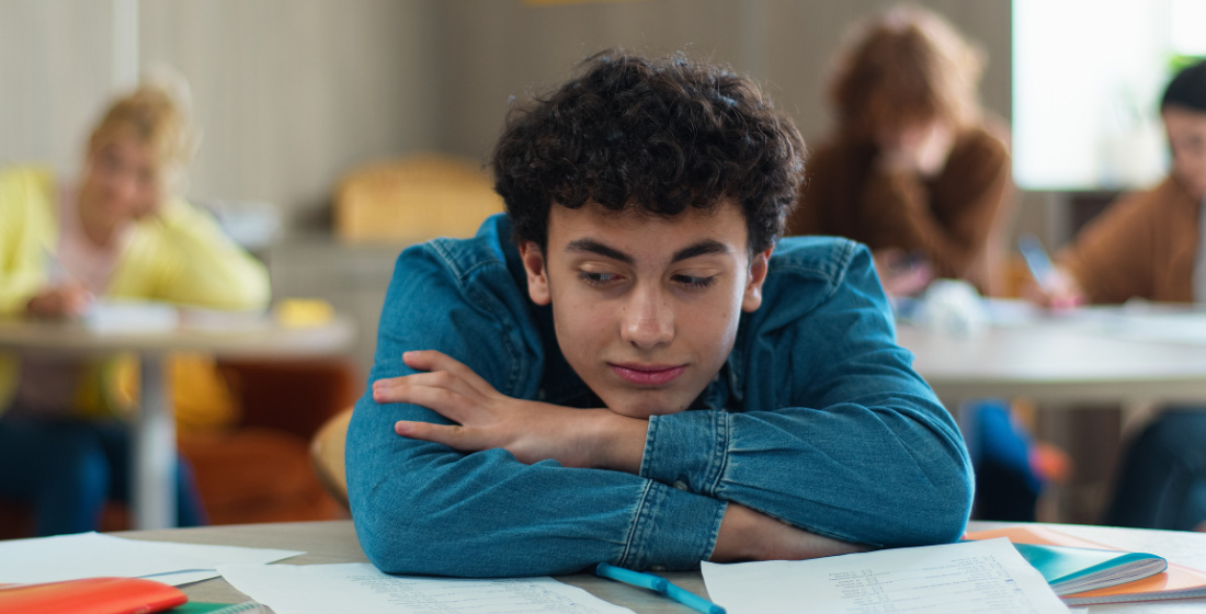 Jongen in de klas die leunt op zijn tafel
