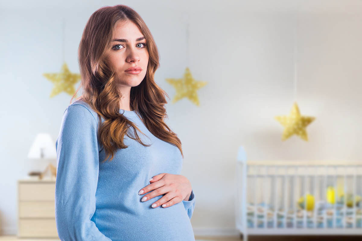 Zwangere vrouw die in de babykamer staat