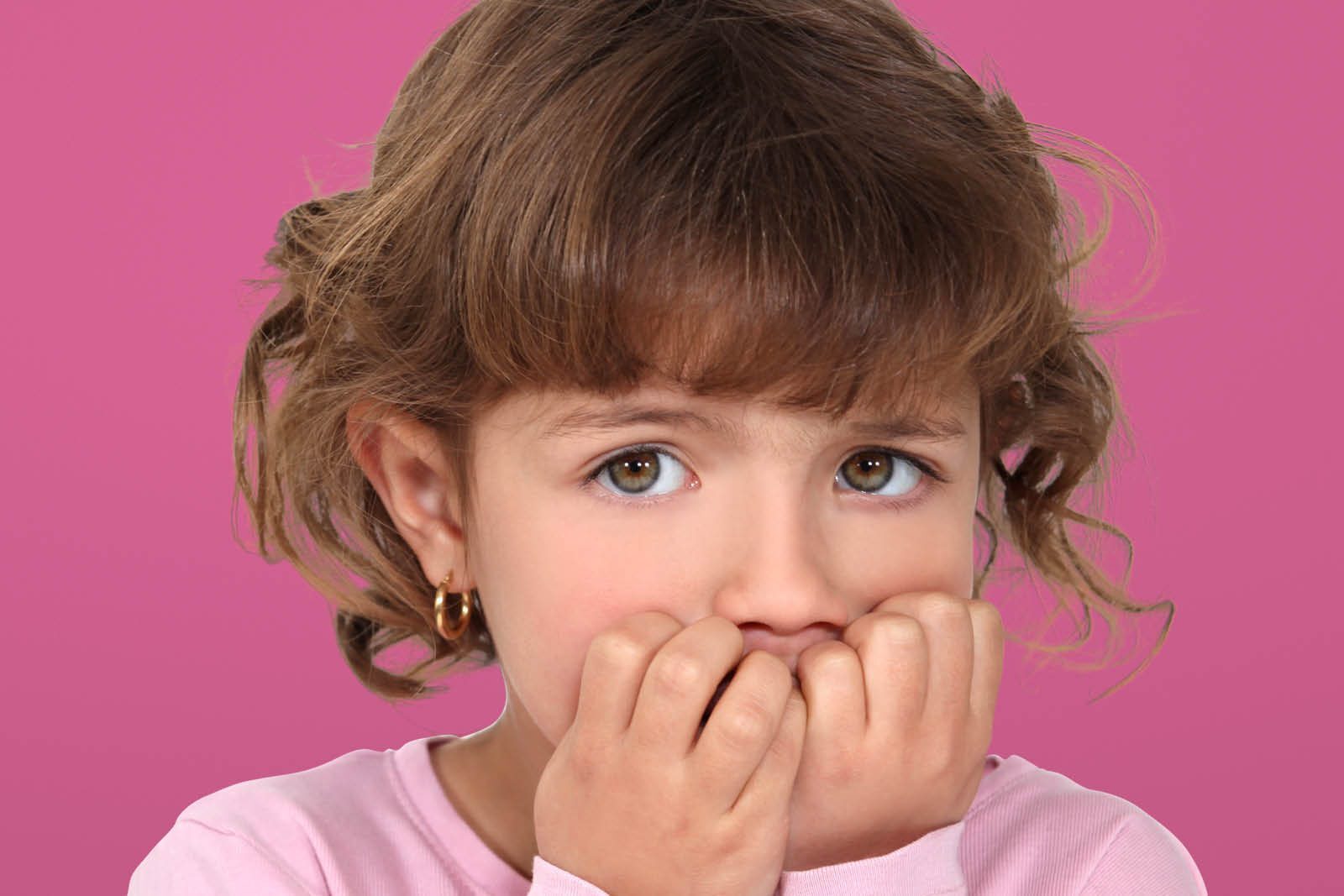 Meisje die bang kijkt en haar handen voor haar mond houdt