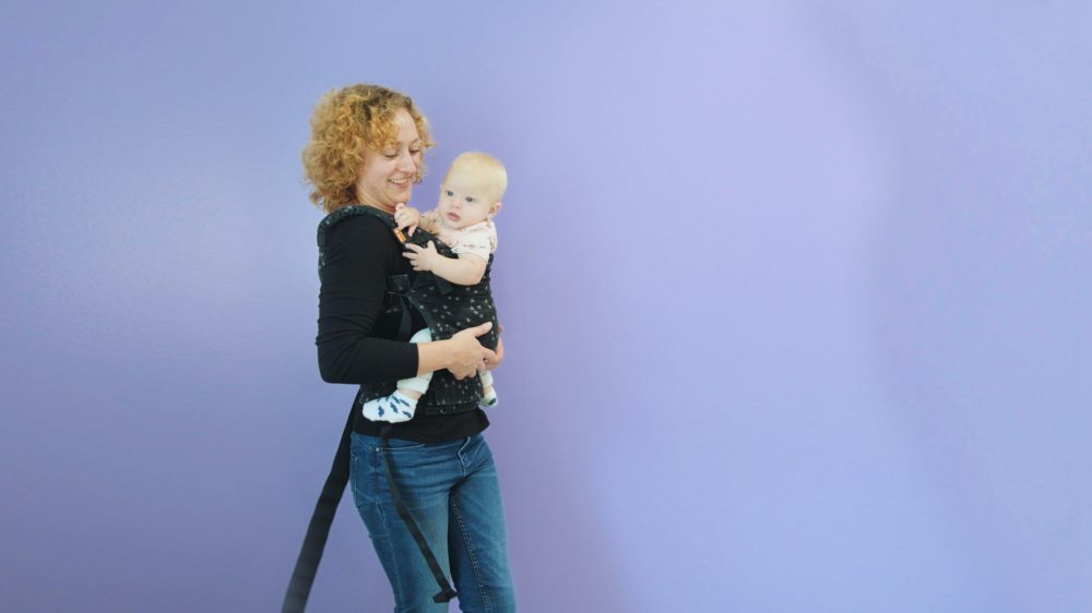 Moeder die baby in draagzak draagt