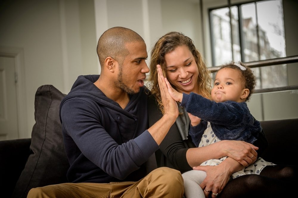 Ouders en dochter geeft een high-five aan de vader