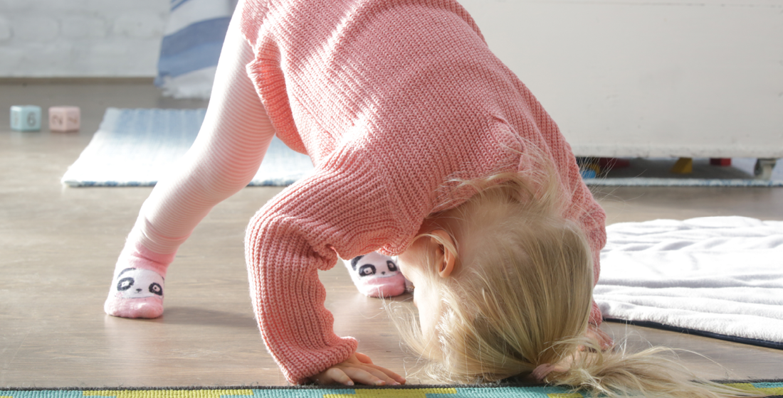 Peuter speelt en kijkt ondersteboven tussen de benen door