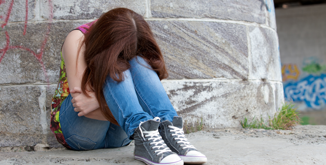 Pubermeisje die buiten ineen gevouwen zit