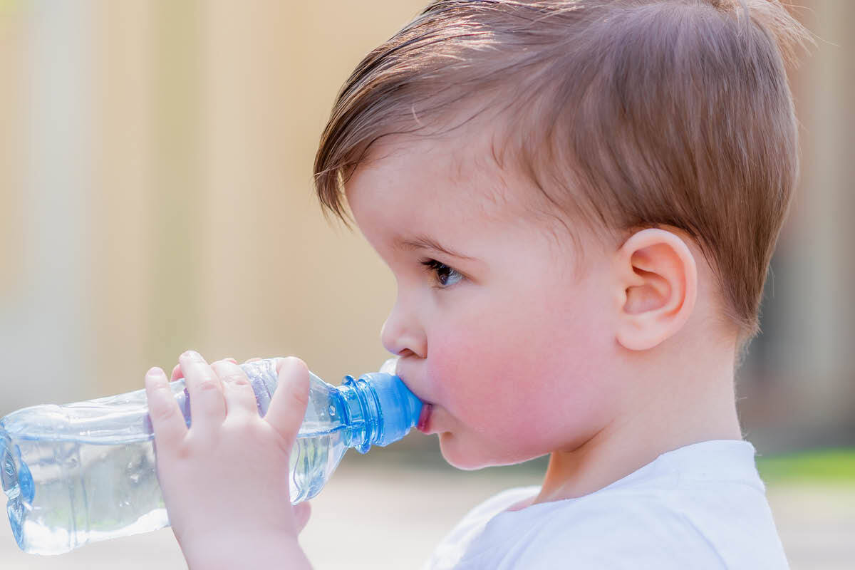 kind die water uit een fles drinkt