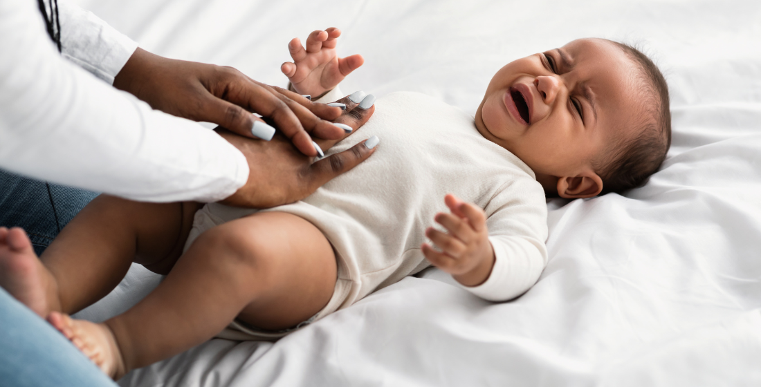 Huilende baby, moeder legt hand op buik