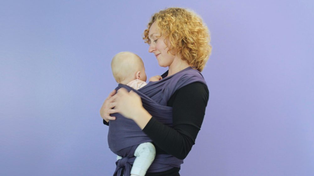 Moeder die baby in een rekbare draagdoek draagt