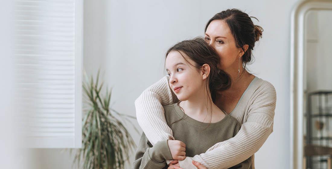 Moeder knuffelt haar puberdochter van achteren
