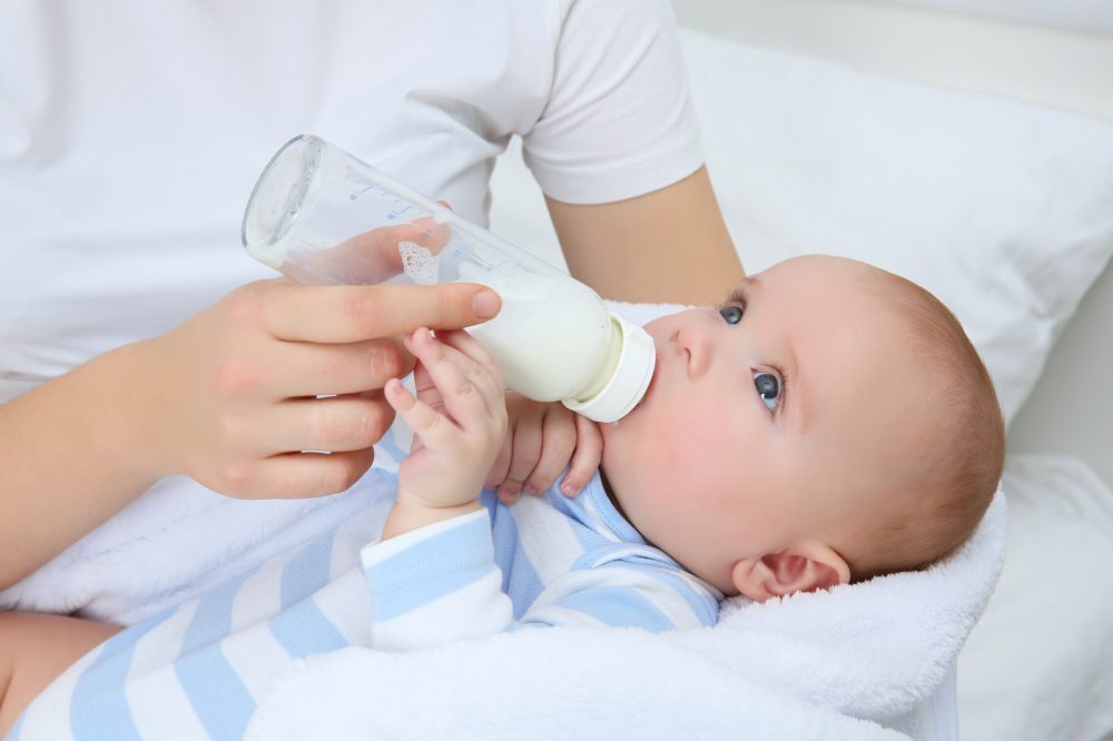 Baby die flesvoeding krijgt en aan het drinken is