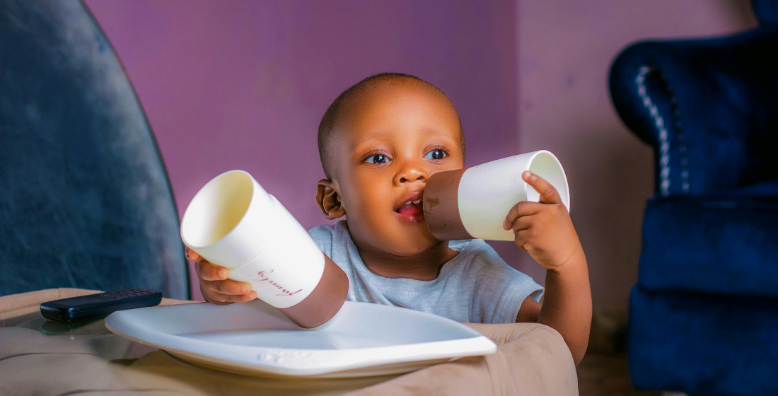 Baby die een drinkbeker in de hand heeft