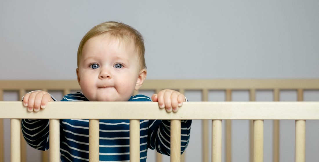 Baby staat in ledikant