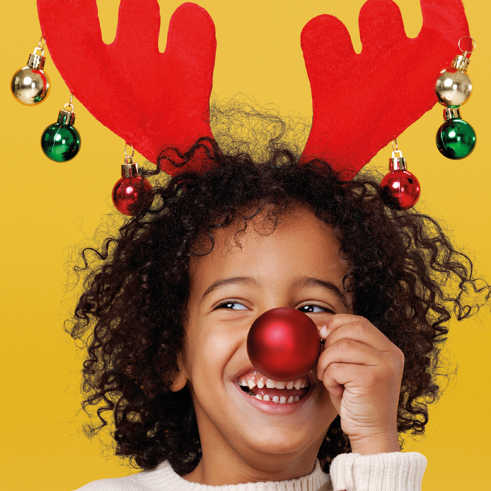 Kindje met rendieroren en kerstbal voor zijn neus