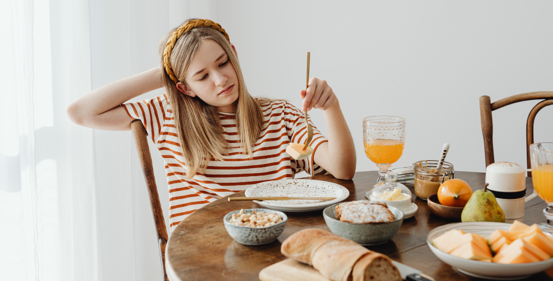 Puber die geen zin heeft om te ontbijten en verveelt naar haar eten kijkt