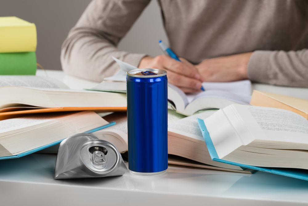 Puber die huiswerk maakt en een energydrankje drinkt
