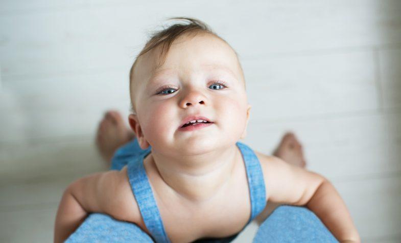 baby die aan de benen van ouder hangt