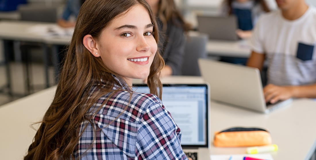 Meisje van 18 jaar zit achter laptop en kijkt om
