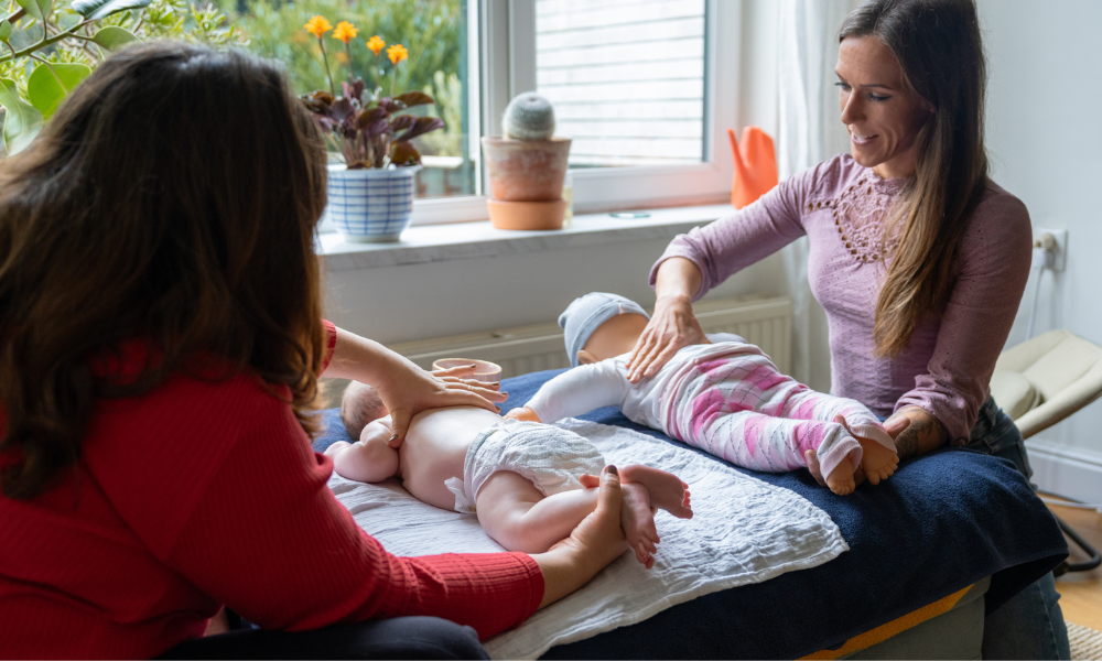Twee vrouwen die een Shantala babymassage geven