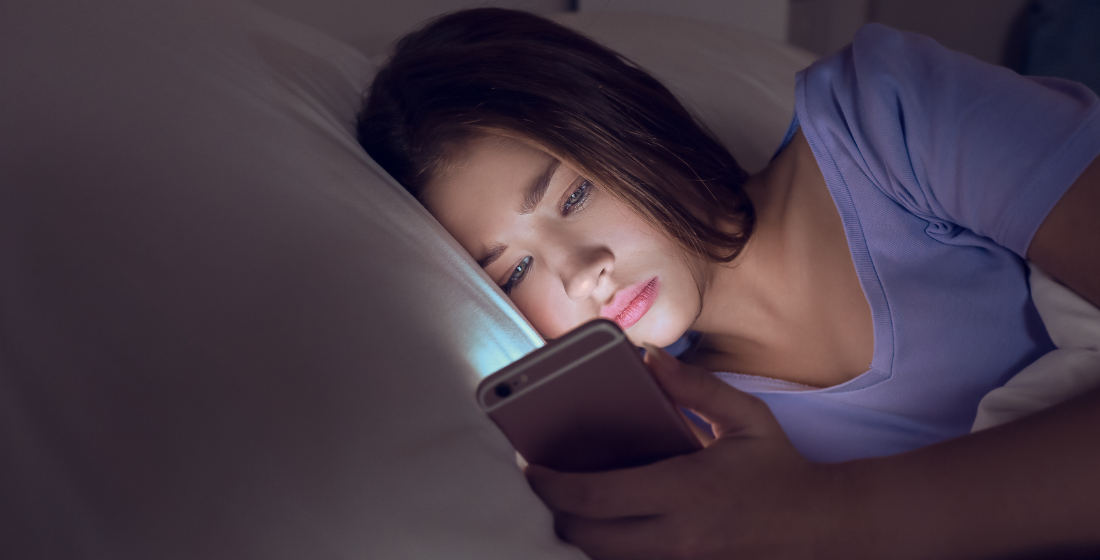 Meisje op haar mobiel aan het scrollen in bed