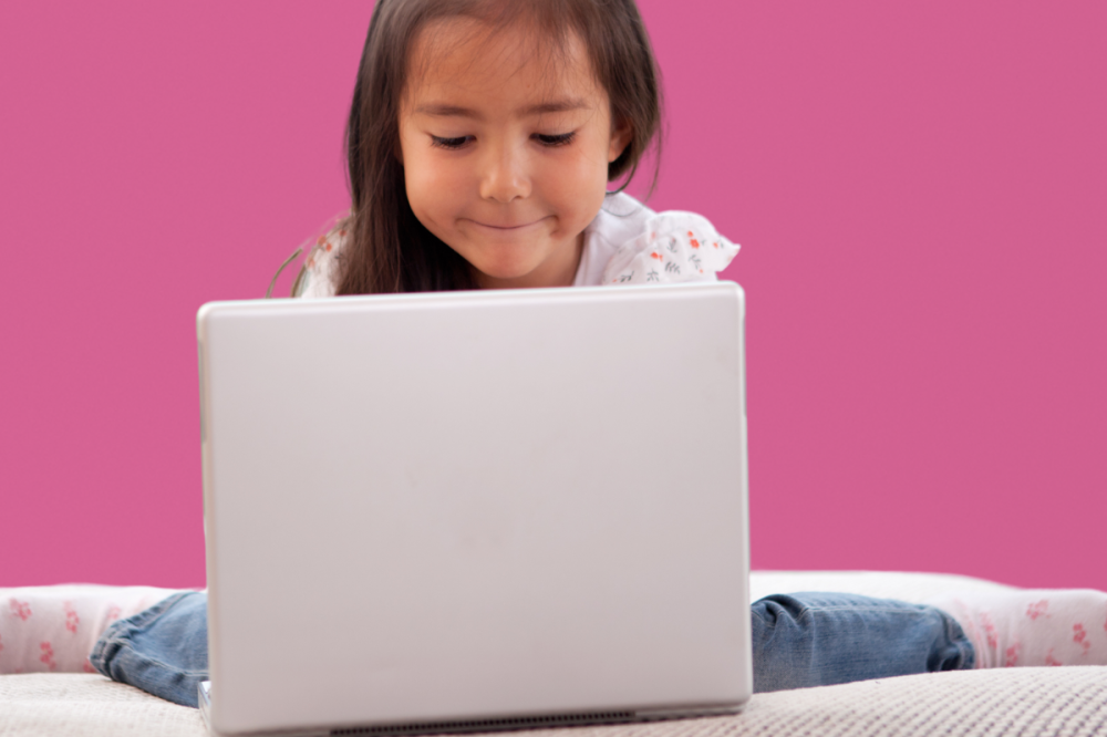 Kind zit op bank achter laptop