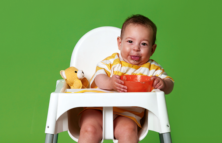 Peuter in kinderstoel kliedert met eten