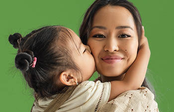 Peuter meisje geeft moeder een kus op de wang