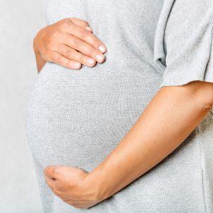 Vrouw houdt haar zwangere buik vast