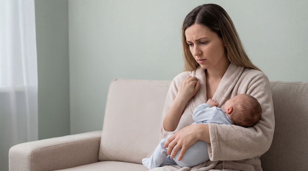 Vrouw die bezorgd kijkt met baby in haar armen