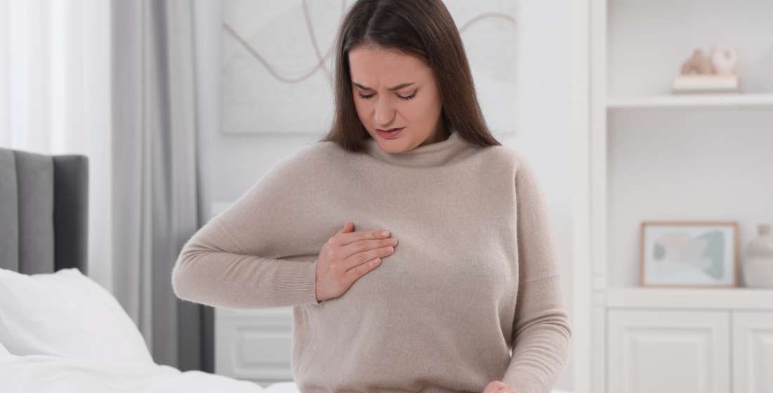 Vrouw die naar haar borst grijpt vanwege pijnlijke stuwing
